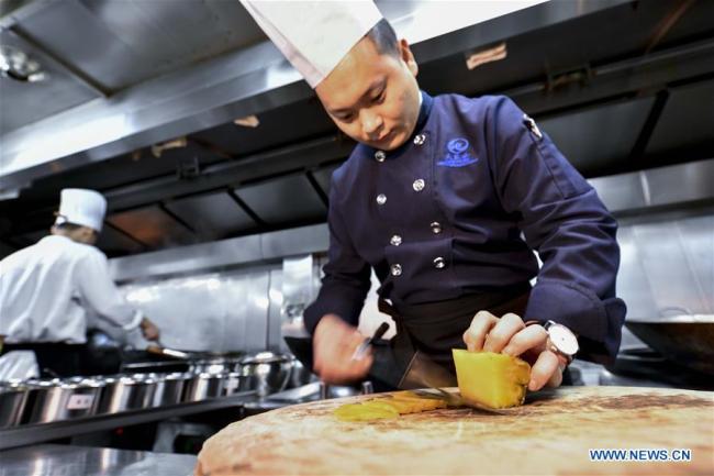 Chef Liu Chong cuts(切 qiè) pickle as he prepares(准备 zhǔnbèi) a dish at a restaurant in southwest China's Chongqing, March 22, 2019. [Photo: Xinhua]